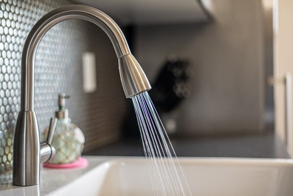 A modern kitchen with a stainless steel faucet and a soap dispenser on the counter.