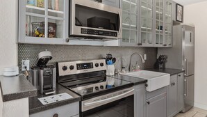 A modern kitchen with stainless steel appliances, a microwave, a stove, and a refrigerator. - Tranquility Octopus Suite - Oceanfront Paradise! (Melbourne Beach)