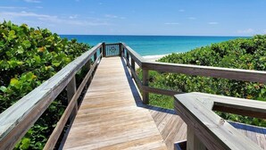 A wooden boardwalk leading to a beach with clear blue water and lush greenery. - Tranquility Octopus Suite - Oceanfront Paradise! (Melbourne Beach)