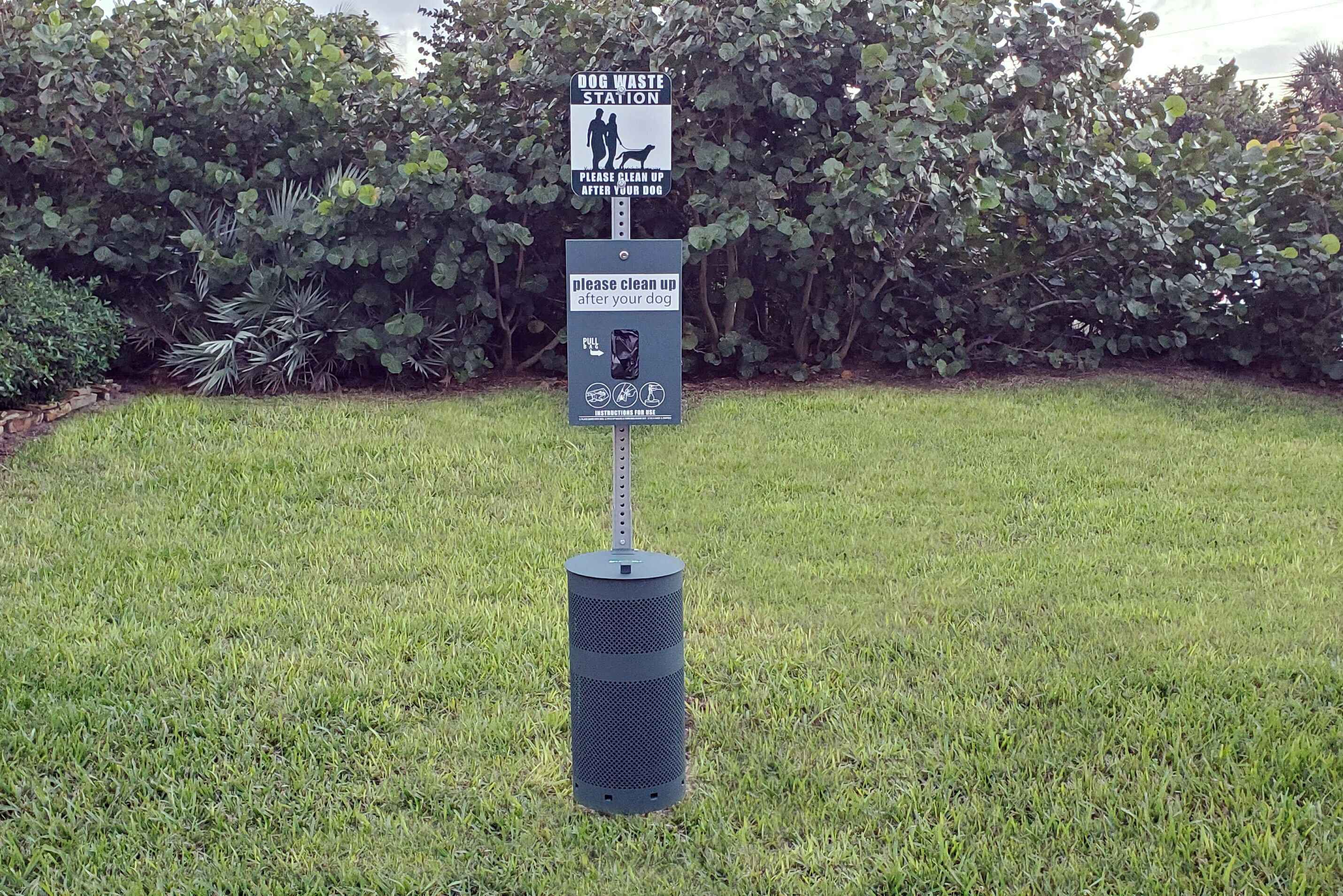 A dog waste station with a sign instructing to clean up after your dog.