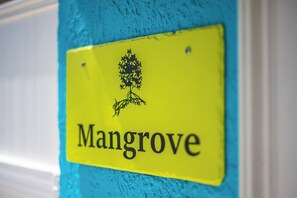 A yellow sign with the word 'Mangrove' and a black tree silhouette.
