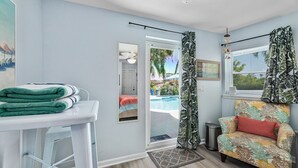 A room with a pool view, a chair, and a table with towels. - Crane Creek Inn Manatee Suite: Waterfront Pool! (Melbourne)