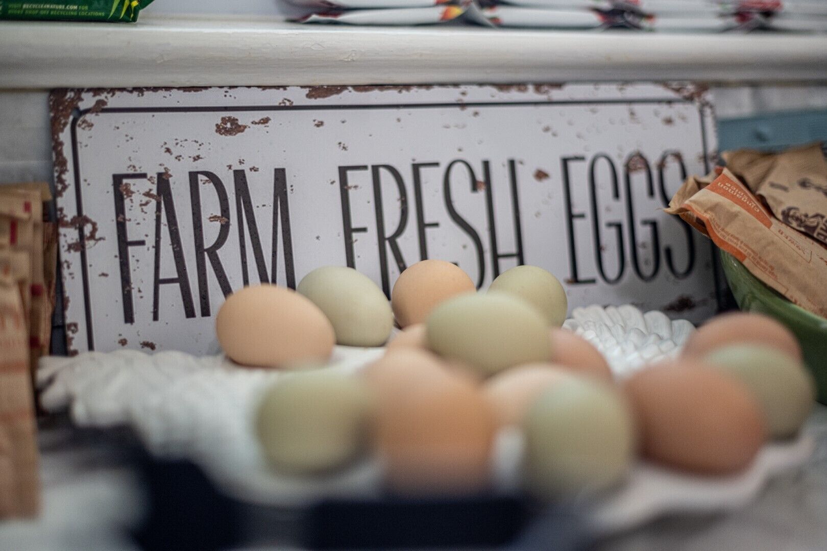Un letrero que dice 'FARM FRESH EGGS' con una cesta de huevos al frente.