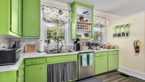 A modern kitchen with green cabinets, a stainless steel sink, and a coffee maker.