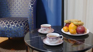 A room with a patterned sofa, a small round table with a tea set and fruit, and a curtain in the background. - Taksim ABC Hotel (Istanbul)