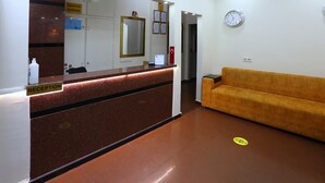 A reception area with a reception desk, a mirror, a clock, and a sofa. - Taksim ABC Hotel (Istanbul)