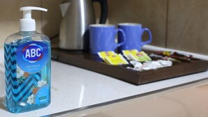 A bathroom counter with a bottle of ABC Sivi Sabun liquid soap, two blue mugs, a silver kettle, and a tray with various toiletries. - Taksim ABC Hotel (Istanbul)