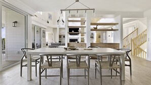 A spacious dining area with a large table and six chairs, surrounded by wooden floors and white walls.