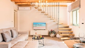 Un salon moderne avec un escalier en bois, un canapé, un téléviseur et un coin repas.