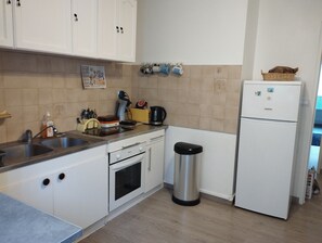 A kitchen with white cabinets, a stainless steel sink, a coffee maker, and a trash can. - Le Pied de Ville, Appartement T3 Dans la Vieille Ville de Digne les Bains (Digne-les-Bains)