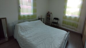 A bedroom with a bed, a nightstand, a chair, and a small cabinet.