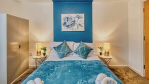 Ein Schlafzimmer mit einem Bett, zwei Nachttischen, einem Schrank und einem Bild an der Wand.