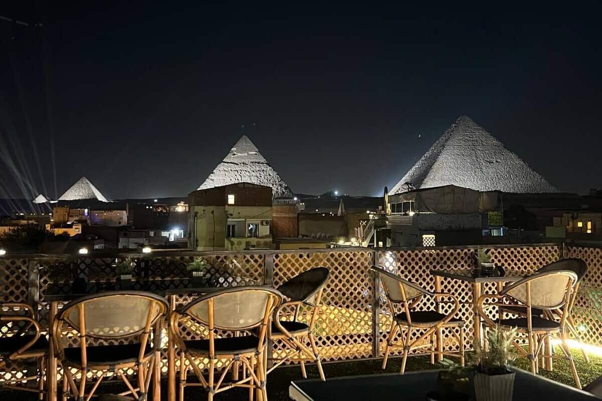 Una terraza en la azotea con estructuras de techo de paja, muebles de mimbre y vistas de los edificios circundantes.