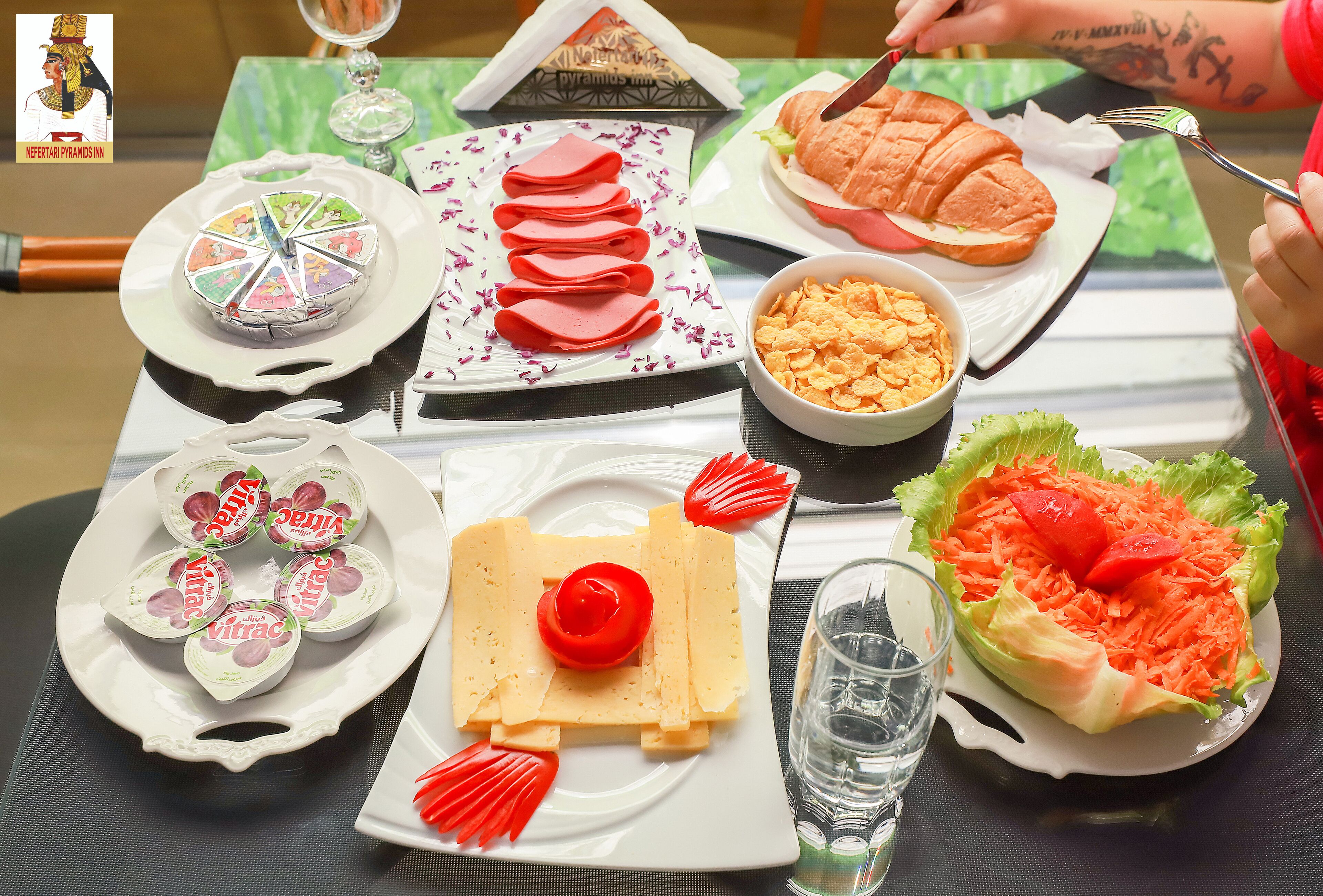 Une table sur laquelle on trouve divers aliments, notamment un gâteau, des tranches de viande, un sandwich et une salade.
