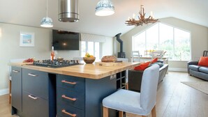 A modern kitchen with a large island, built-in appliances, and a large window providing natural light.