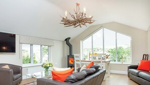 A modern living room with a fireplace, leather sofas, a dining table, and large windows.