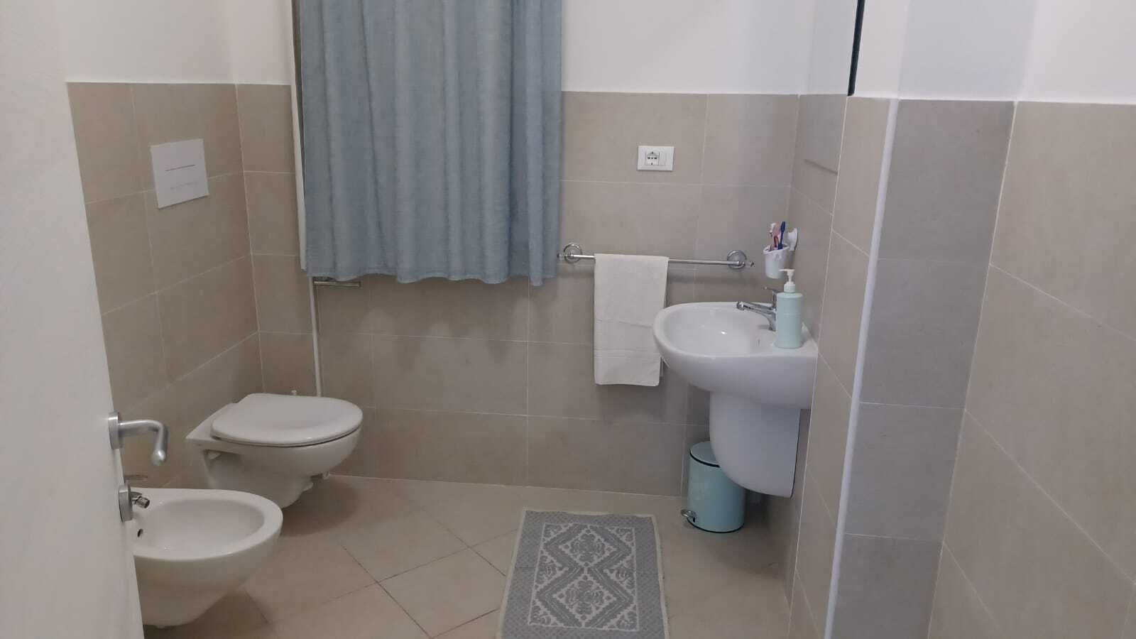 Une petite salle de bain avec deux toilettes, un lavabo et une douche.