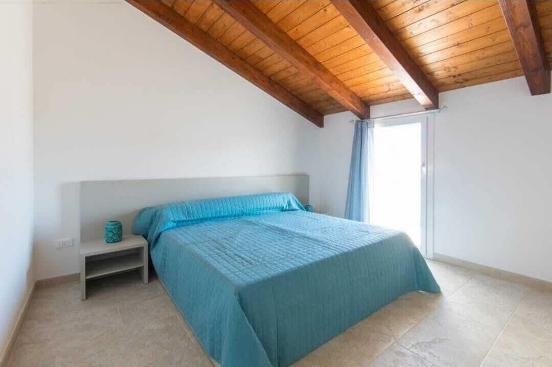 Ein Schlafzimmer mit einem Bett, einem Nachttisch und einem Fenster mit Vorhängen.