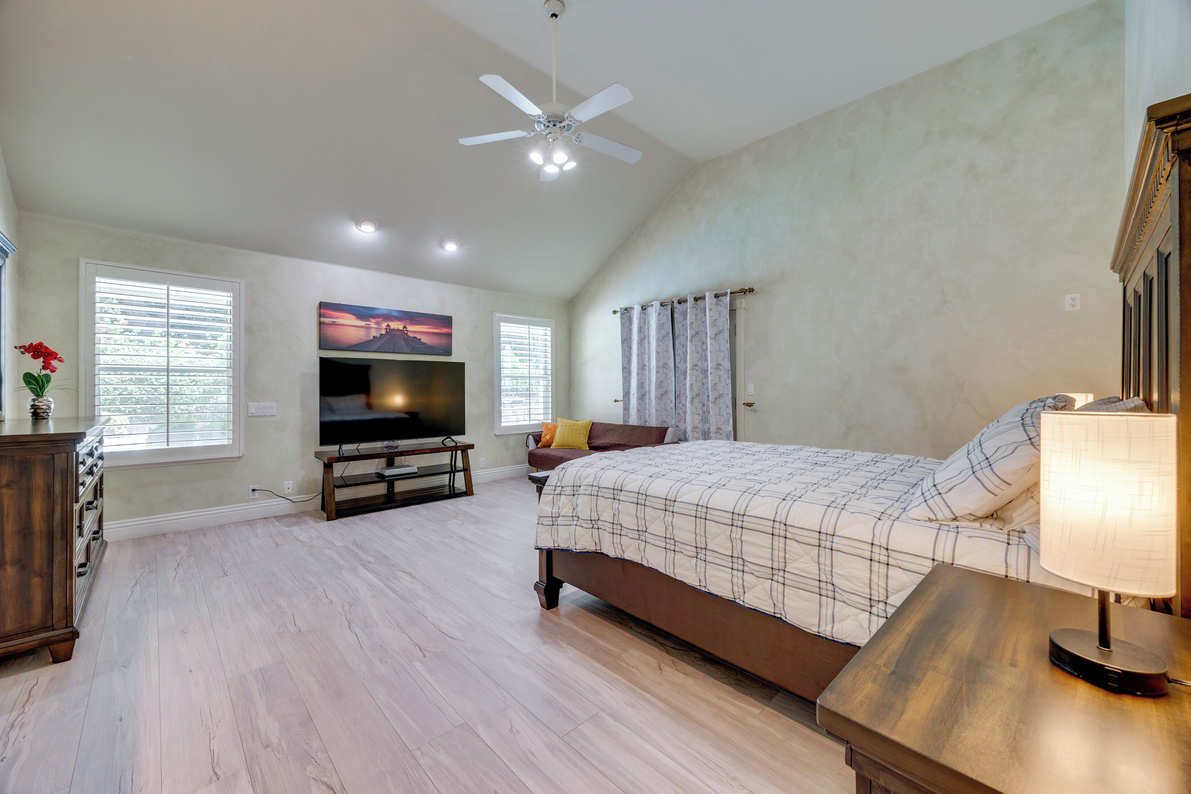 A bedroom with a large bed, a television, and a ceiling fan.