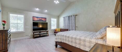 A bedroom with a large bed, a television, and a ceiling fan.