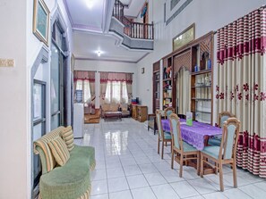 Uma sala de estar ampla com área de jantar, com sofá, mesa de jantar, cadeiras e escada.