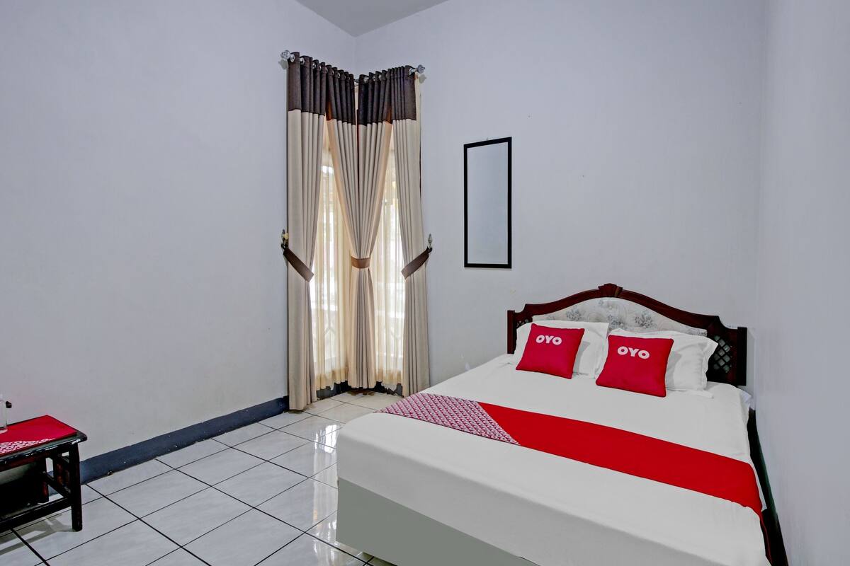 A neatly arranged bedroom with a bed, a bedside table, and curtains.