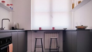A modern kitchen with a window, two stools, a sink, and cabinets. - Florence Design Apartment (Firenze)
