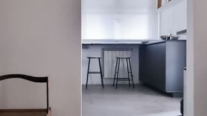 A minimalist kitchen with a large window, a wooden chair, and two stools. - Florence Design Apartment (Firenze)