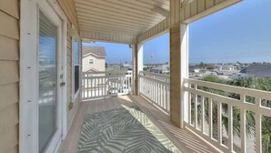 A covered balcony with a view of the beach and buildings. - Pet Friendly - 3 BR 3.5 BA  Pool  Garage 2 Balconies  2 blocks to Beach!! (Corpus Christi)