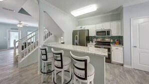 A modern kitchen with white cabinets, a central island, and bar stools. - Pet Friendly - 3 BR 3.5 BA  Pool  Garage 2 Balconies  2 blocks to Beach!! (Corpus Christi)