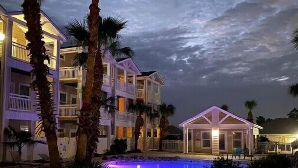 A resort with a swimming pool, palm trees, and a two-story building with balconies. - Pet Friendly - 3 BR 3.5 BA  Pool  Garage 2 Balconies  2 blocks to Beach!! (Corpus Christi)