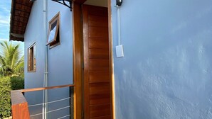 A modern building with a wooden door, a small window, and a security camera. - RiqueHouse Hidro churrasqueira a 500 m (Marica)