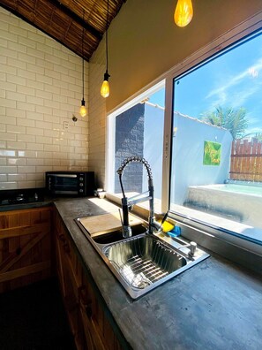 Eine Küche mit Einbauofen, Spüle mit modernem Wasserhahn und Fenster mit Blick ins Freie.