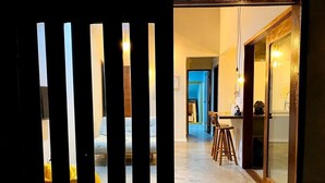 A hallway with a kitchen area visible through a glass door. - RiqueHouse Hidro churrasqueira a 500 m (Marica)