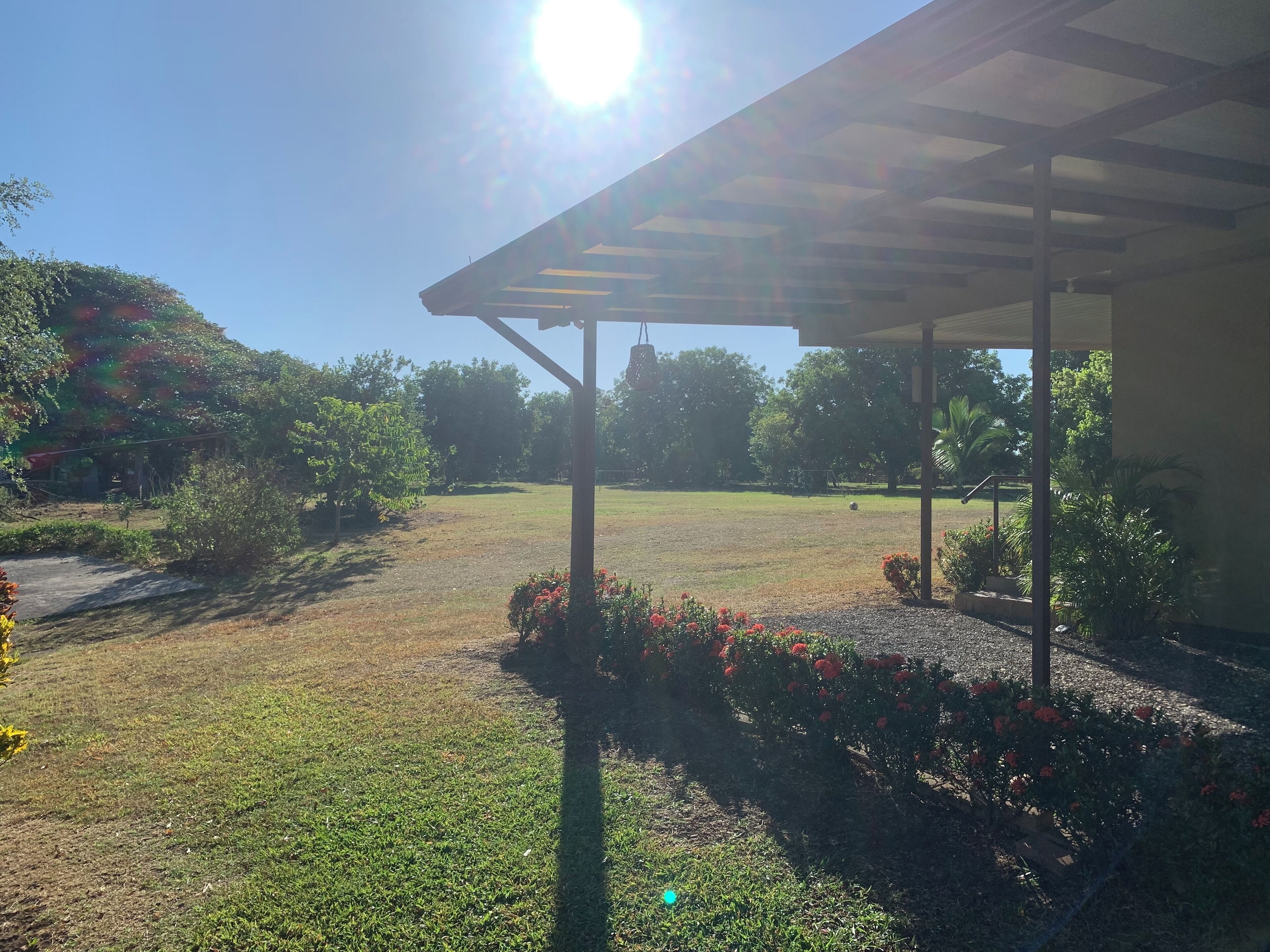 A covered outdoor area with a grassy lawn and a pergola structure.