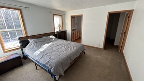 A bedroom with a bed, a nightstand, a dresser, a window, and a door leading to a bathroom. - NEW LISTING - FARMHOUSE --VERY CLOSE TO SNOWMOBILE TRAILS - VERY PRIVATE (Brimley)