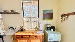 Una cucina con un armadietto in legno, un frigorifero vintage, una moka e una finestra con tende.