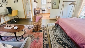 A modern bedroom with a bed, a desk, a chair, and a dining area. - Hill Country Bungalow at Mosaic (San Marcos)