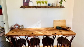 Un tavolo da pranzo in legno con quattro sedie, una parete bianca con due mensole rustiche e una testiera in legno.