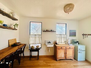A compact kitchen with wooden cabinetry, a dining table with chairs, a sink, and a vintage refrigerator. - Hill Country Bungalow at Mosaic (San Marcos)