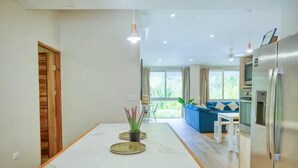 Eine moderne Küche mit Marmorarbeitsplatte, ein Essbereich mit blauem Sofa und Blick auf Grünfläche.