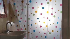 A bathroom with a sink, toilet, and shower curtain with polka dots.
