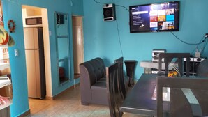 A room with bunk beds, a microwave, a refrigerator, a TV, and a dining table with chairs.