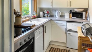 Een compacte keuken met een vaatwasser, een magnetron en een kleine koelkast.