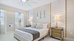 Une chambre à coucher moderne avec un grand lit, des tables de chevet et un ventilateur de plafond.