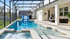 Une piscine avec un jacuzzi, un espace couvert et des sièges à l’extérieur.