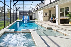 A swimming pool with a hot tub, a covered area, and outdoor seating.