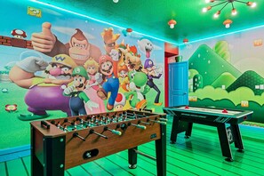 Une pièce équipée d’un baby-foot, d’une fresque murale sur le thème de Mario et d’une console Nintendo Switch.