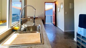 A modern kitchen with a large window, a sink, and a wooden countertop. - RiqueHouse Hidro Piscina a 500m da praia (Marica)