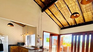 A spacious kitchen with a large island, wooden bar stools, and a bench. - RiqueHouse Hidro Piscina a 500m da praia (Marica)